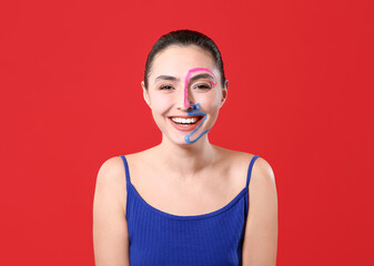 Beautiful young woman with paint on her face against color background