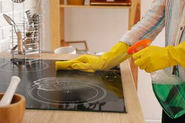 Woman cleaning stove in kitchen, closeup