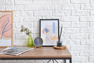 Table with pictures and decor near brick wall