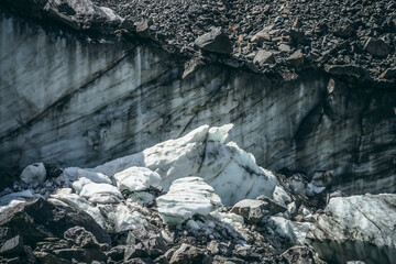 Nature background with icefall near glacier wall with cracks and scratches. Natural backdrop with icy wall and blocks of ice. Beautiful landscape with shiny glacial wall and ice blocks in sunlight.