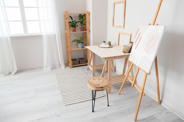 Fototapeta premium Modern workplace and easel in interior of stylish room