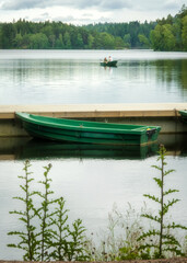 Green boat waiting for customer in the background young couple paddling canoe in swedish lake near gothenburg