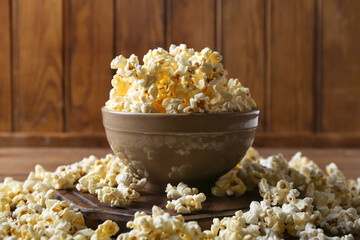 Bowl with tasty popcorn on wooden background