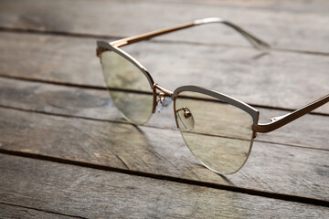 Stylish eyeglasses on wooden background, closeup