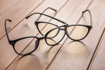 Different stylish eyeglasses on color wooden background, closeup