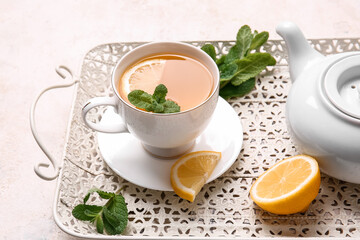 Tray with cup of tasty green tea, pot and ingredients on grunge background