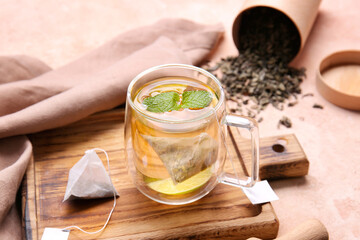 Wooden board with cup of tasty green tea on color background