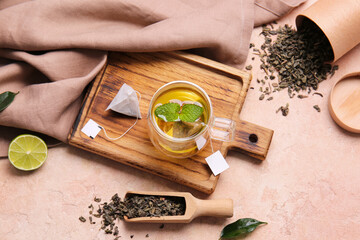 Wooden board with cup of tasty green tea on color background