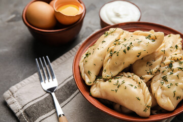 Bowl with tasty dumplings on grunge background, closeup