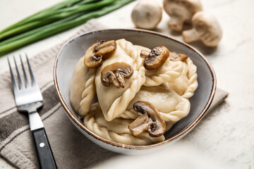 Bowl with tasty dumplings on light background