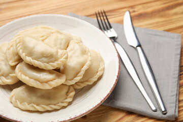 Plate with tasty dumplings on wooden background, closeup