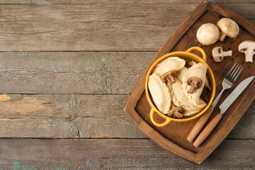 Board with tasty dumplings and mushrooms on wooden background