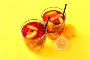 Glasses of tasty ice tea with fruits on color background