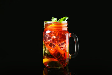 Mason jar of tasty ice tea with fruits on dark background - Powered by Adobe