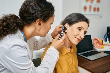 Fotobehang Hearing exam for elderly citizen people. Otolaryngologist doctor checking mature woman's ear using otoscope or auriscope at medical clinic © Peakstock