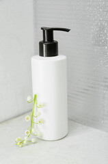 Fototapeta na wymiar Bottle of cream and lily-of-the-valley flowers on light background