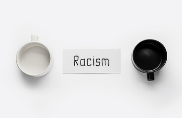 Paper piece with word RACISM and cups on white background
