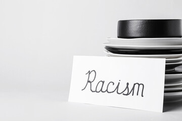 Paper piece with word RACISM and plates on white background