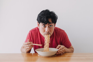Asian man eat instant noodle very deliciously.