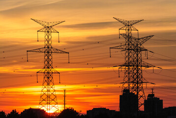 Electric poles and power lines in a Canadian suburban area on an orange vibrant sunset sky background
