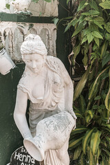 Biała rzeźba z kamienia przedstawiająca kobietę w ogrodzie. - obrazy, fototapety, plakaty