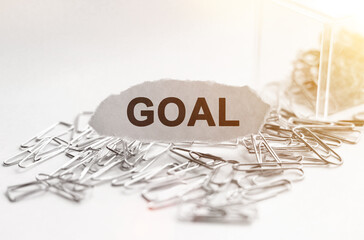 Fototapeta premium Paper clips are scattered on the table and there is paper with the inscription - GOAL