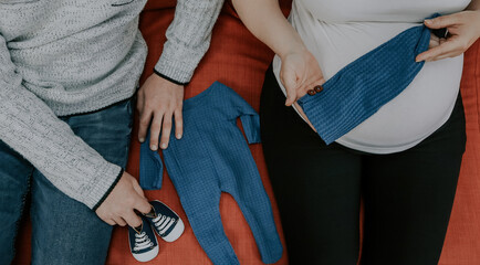 Couple is holding newborn baby's things.


Couple holding newborn baby's things while sitting on sofa, top view close-up.