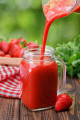 strawberry juice pouring from jug into glass
