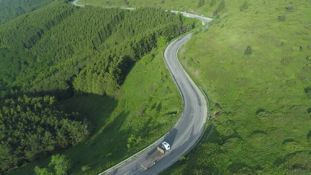 Empty wood transportation truck drving on curvy forest mountain road