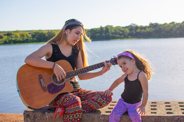 mamá e hija cantando y tocando la guitarra al aire libre 