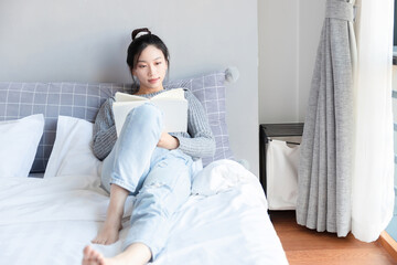 Asian girl reading a book in bed