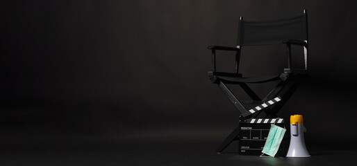 Black director chair , face mask, megaphone and Clapper board or movie slate on black background.