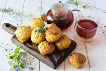 Sweet carrot cupcakes, a cup of tea and a kettle with hot tea for breakfast on a white table.