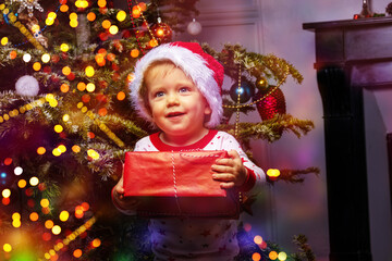 Smiling toddler hold present box by Christmas tree