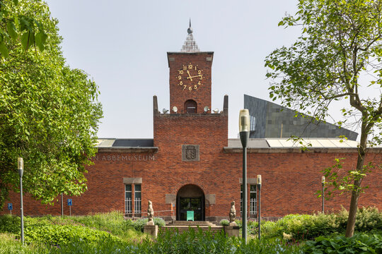 Eindhoven, The Netherlands June 18th 2021. Entrance of the modern art museum Van Abbemuseum exterior facade in Eindhoven city with a clock, trees, greenery and flowers on a sunny day