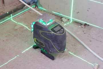 the laser level stands on the floor and draws levels for the installation of building materials