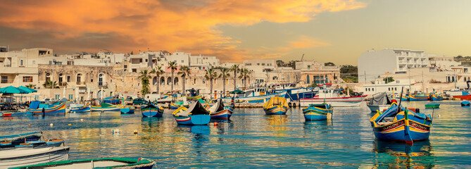 Panoramic view of Marsaxlokk village harbor of Malta, illuminated by sunset light