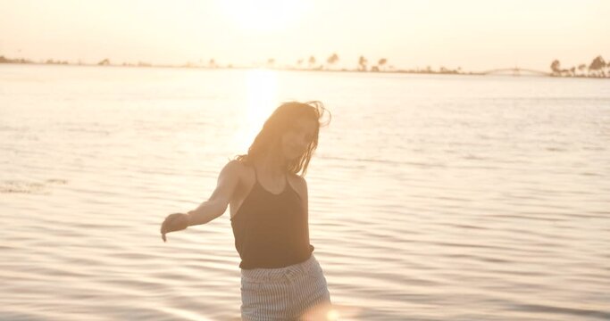 Young beauty woman is dancing on seaside, beach. Happy, relaxation sunset time, freedom concept. Funny dancer, happiness.