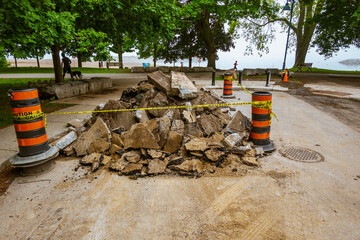 Torn up and piled asphalt paving on a residential street part  of water system repair project in a...