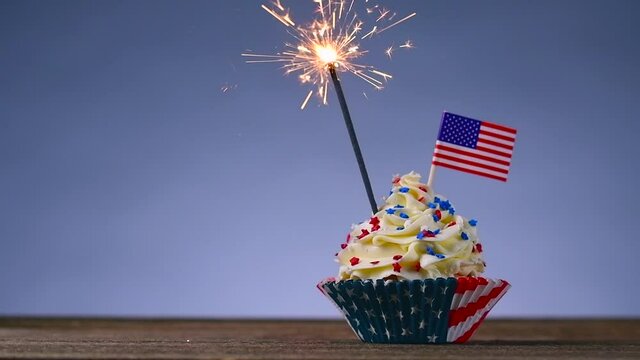 Cupcake American Flag. Sparklers or fireworks lights burning in a cake. 4th of July, Independence, Presidents Day. Tasty cupcakes with white cream icing and colored stars sprinkles. Sweet dessert.