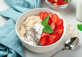 A plate of oatmeal with strawberries, yogurt and chia seeds. Healthy breakfast.