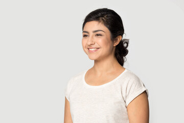 Side view of smiling Indian young woman isolated on grey studio background look in distance dreaming thinking. Happy mixed race female make plan or visualize imagine. Planner, vision concept.