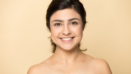 Profile picture of smiling young naked Indian woman isolated on yellow studio background show natural beauty. Headshot portrait of happy millennial mixed race female feel fresh. Skincare concept.