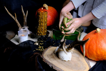 children play with a green witchcraft potion, table is covered with a black cloth, pumpkins lie, animal skulls, candles are burning, the concept of the Halloween holiday, love spell, children's party