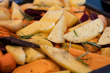 Freshly cut and seasoned vegetables ready for oven baking. Preparing roasted vegetables on oven tray.