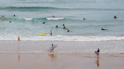 Surfing in Biarritz, France. Surfers on the beach and in the ocean. Active holidays in France.