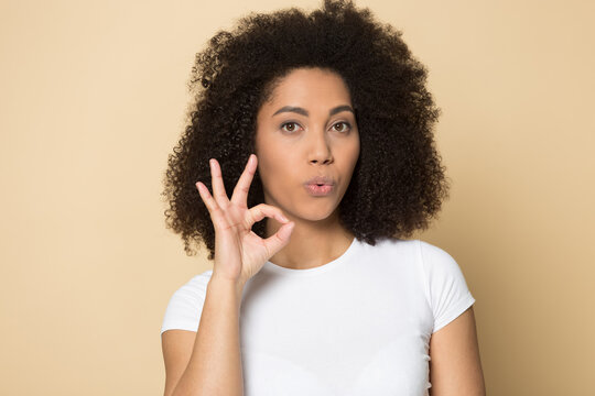 Headshot portrait of young African American woman isolated on yellow studio background show all right hand gesture. Profile picture of biracial female demonstrate ok sign. Nonverbal concept.