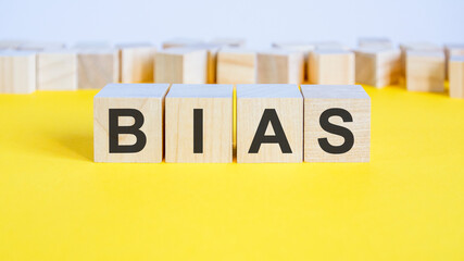 bias word on wooden building blocks lying on the yellow table, concept