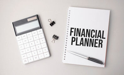 The word FINANCIAL PLANNER is written on a white background next to a pen ,calculator and reports. Business concept