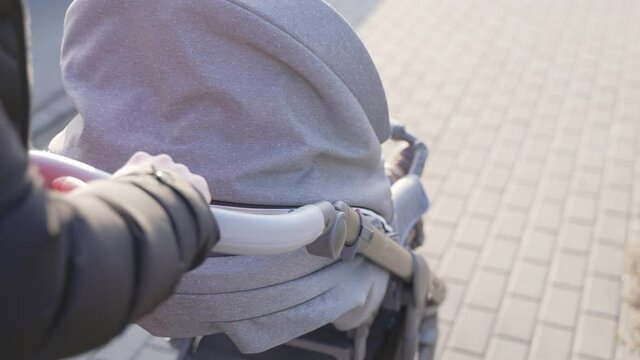 Mom taking a walk with baby in the puschair. Close up on the hands. High quality photo